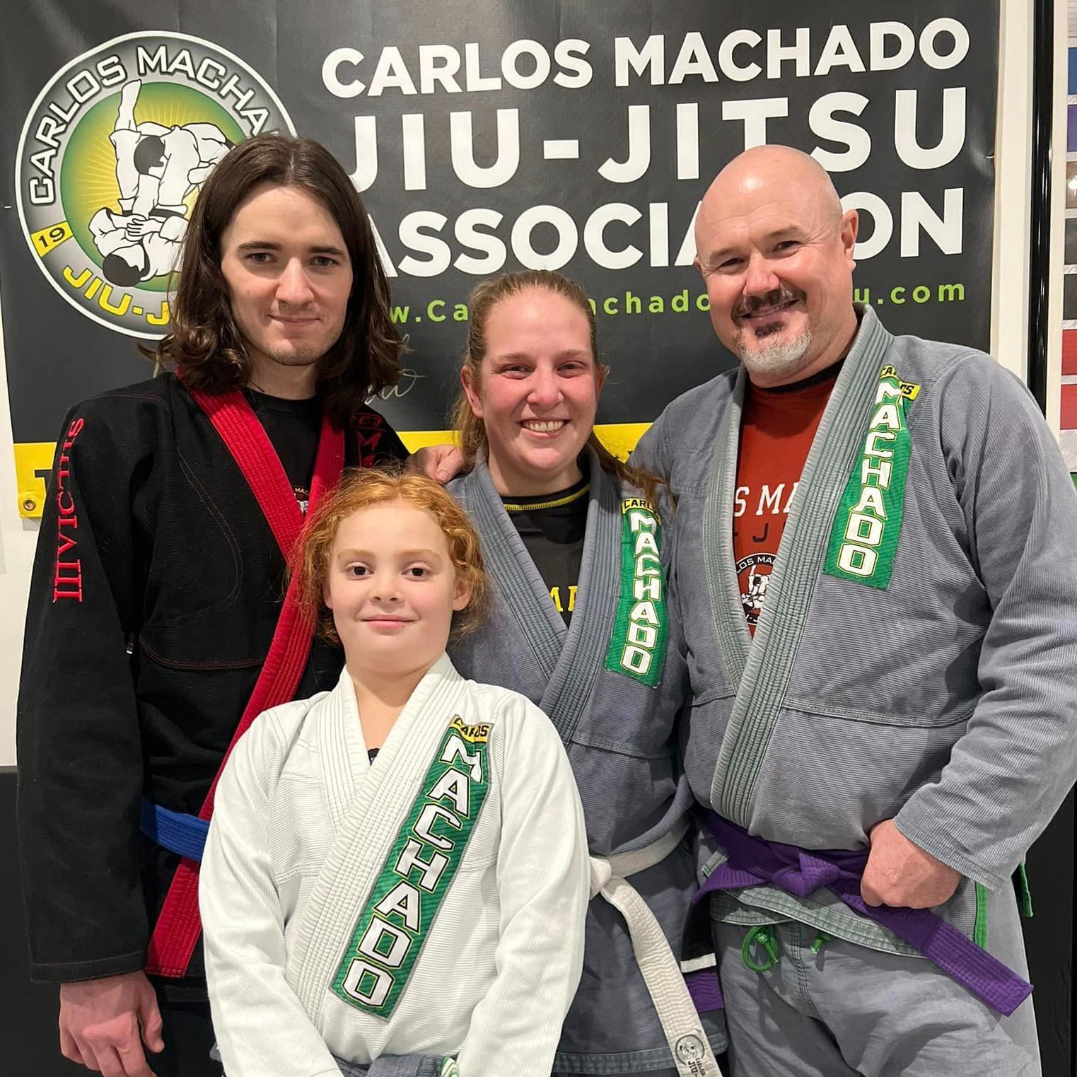 A group of people standing in front of a sign that says carlos machado jiu-jitsu association