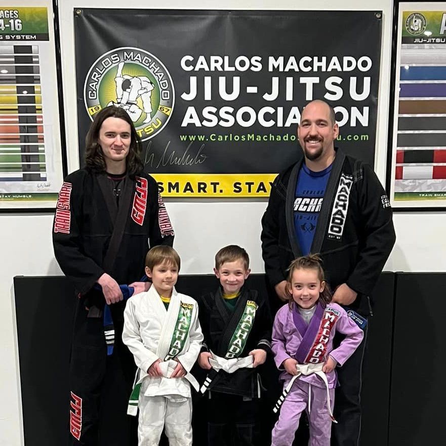 A group of people standing in front of a sign that says carlos machado jiu-jitsu association