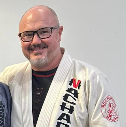 A man wearing glasses and a karate uniform with the word maha on it