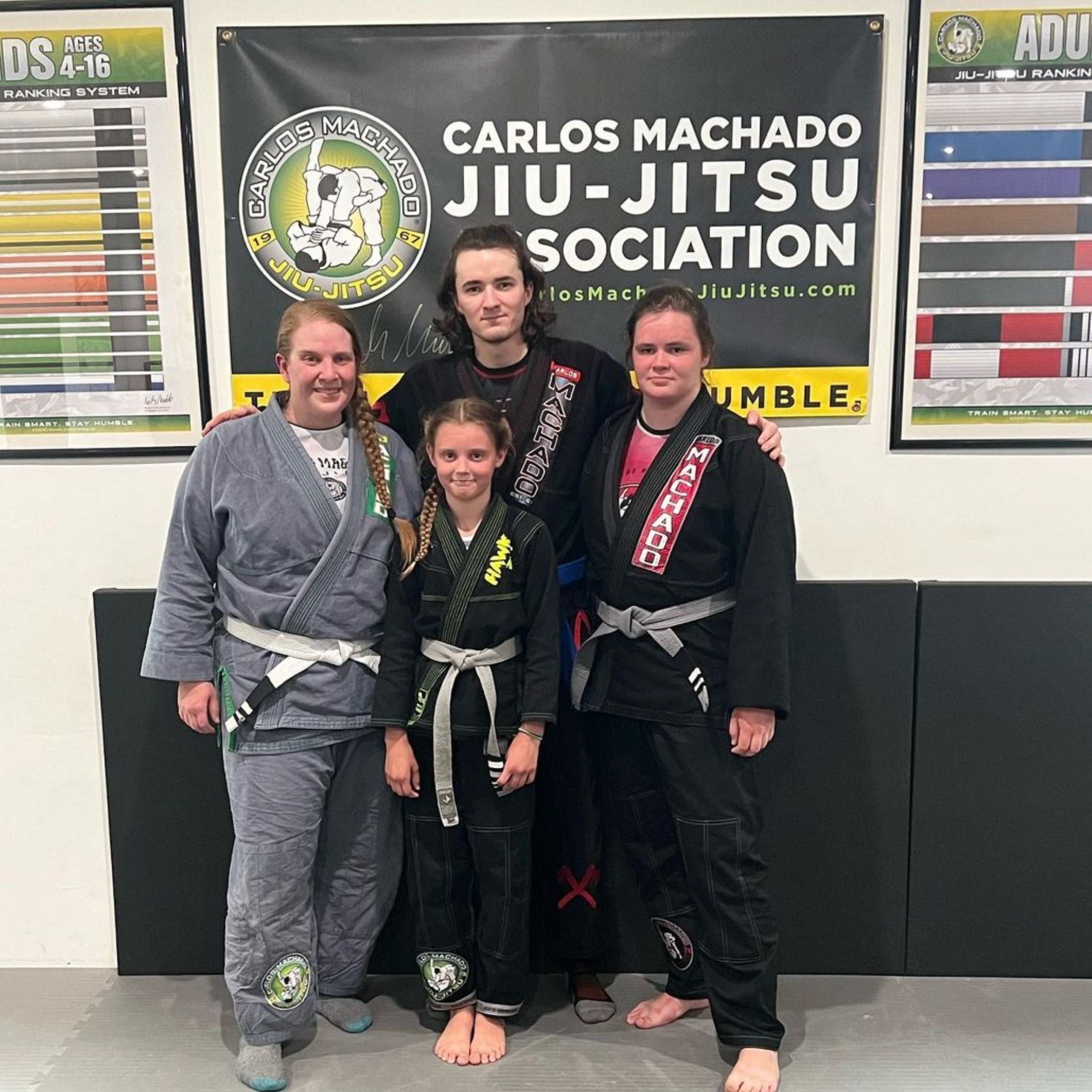 A group of people standing in front of a sign that says carlos machado jiu-jitsu sociation