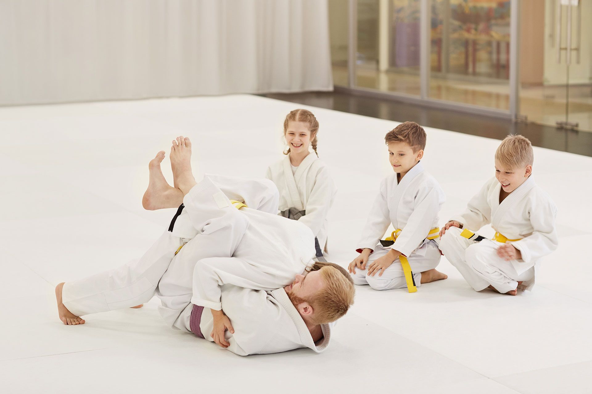 A group of children are practicing judo in a gym.