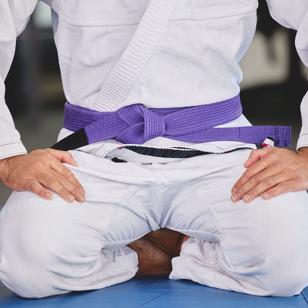 A man in a white karate uniform with a purple belt