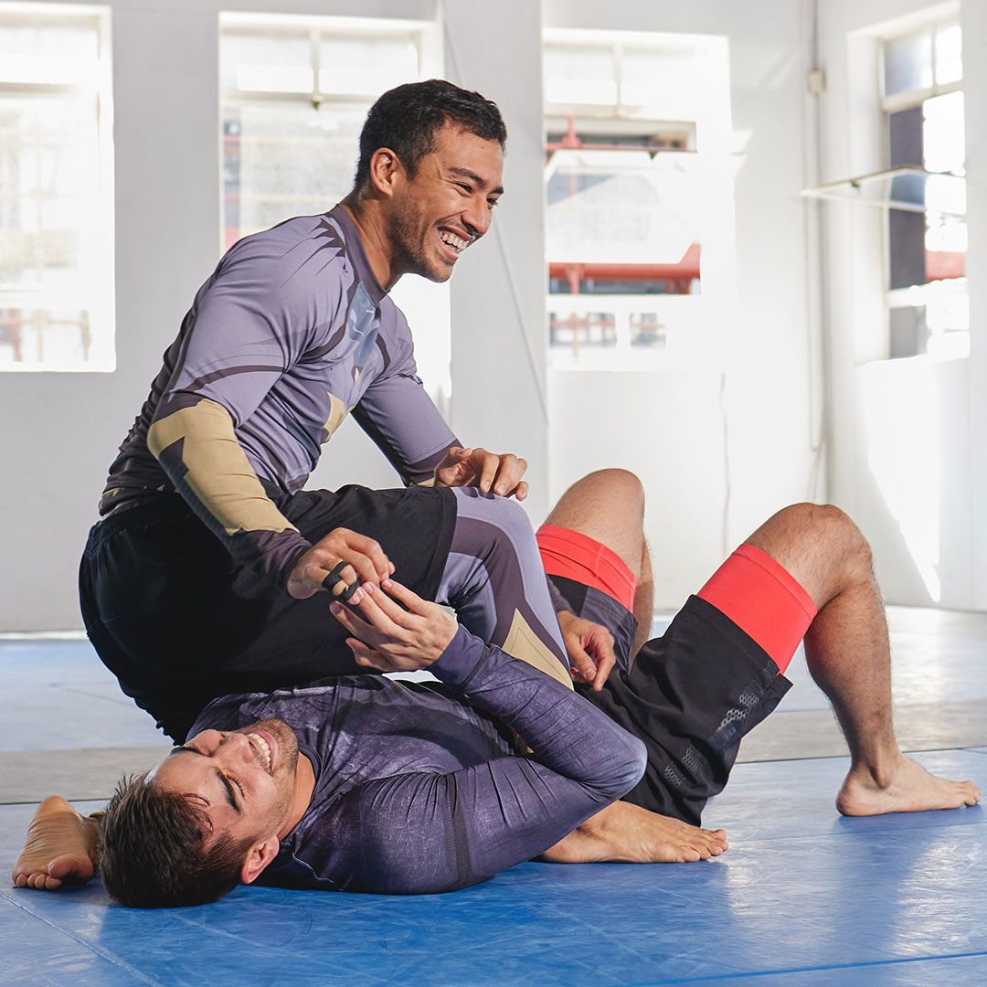 Two men are wrestling on a mat in a gym.