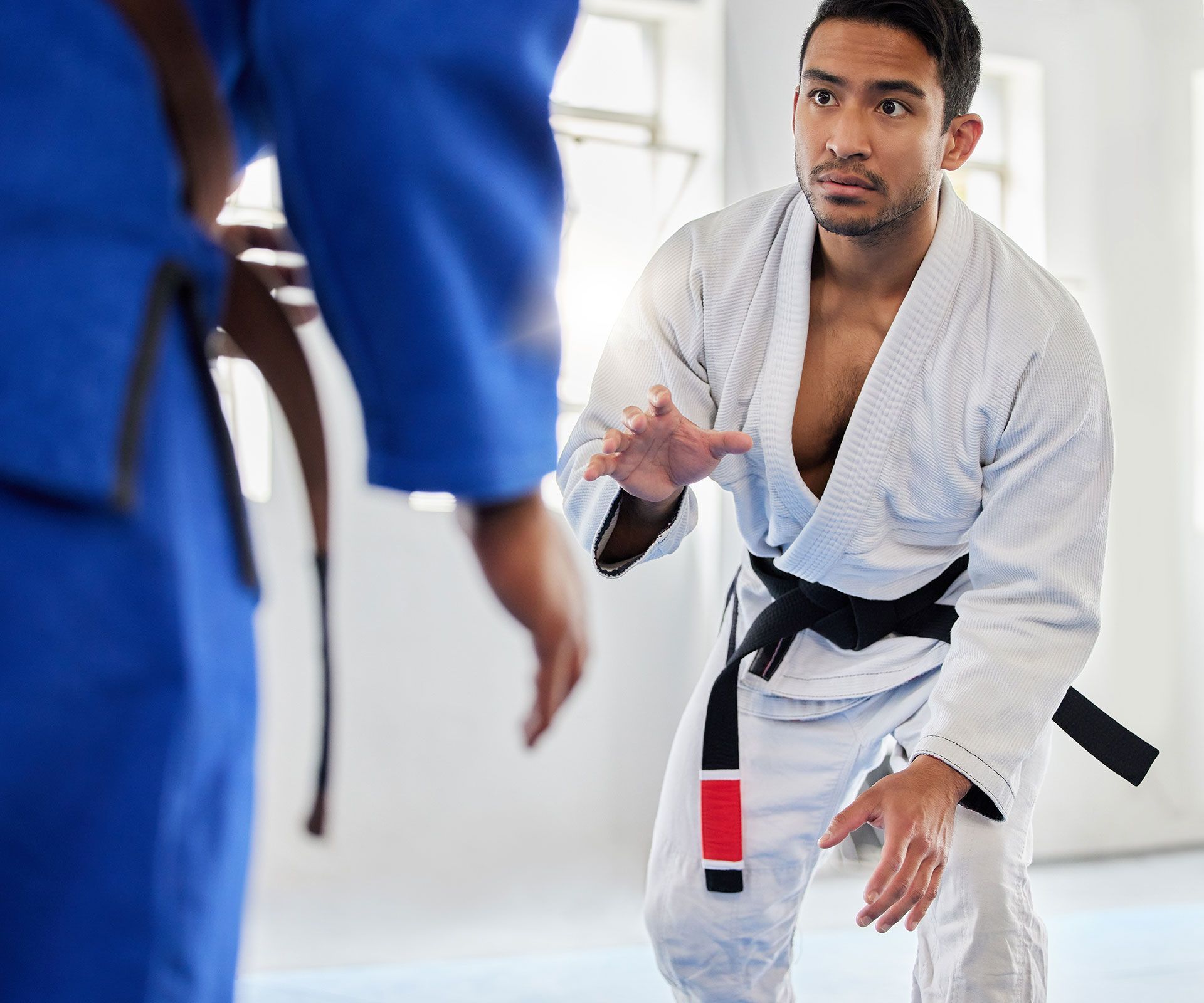 A man in a white kimono with a black belt is standing next to another man in a blue kimono.