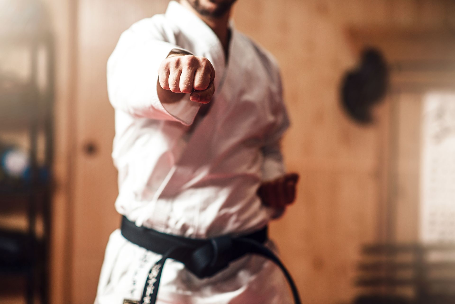 A man in a karate uniform is pointing at the camera.