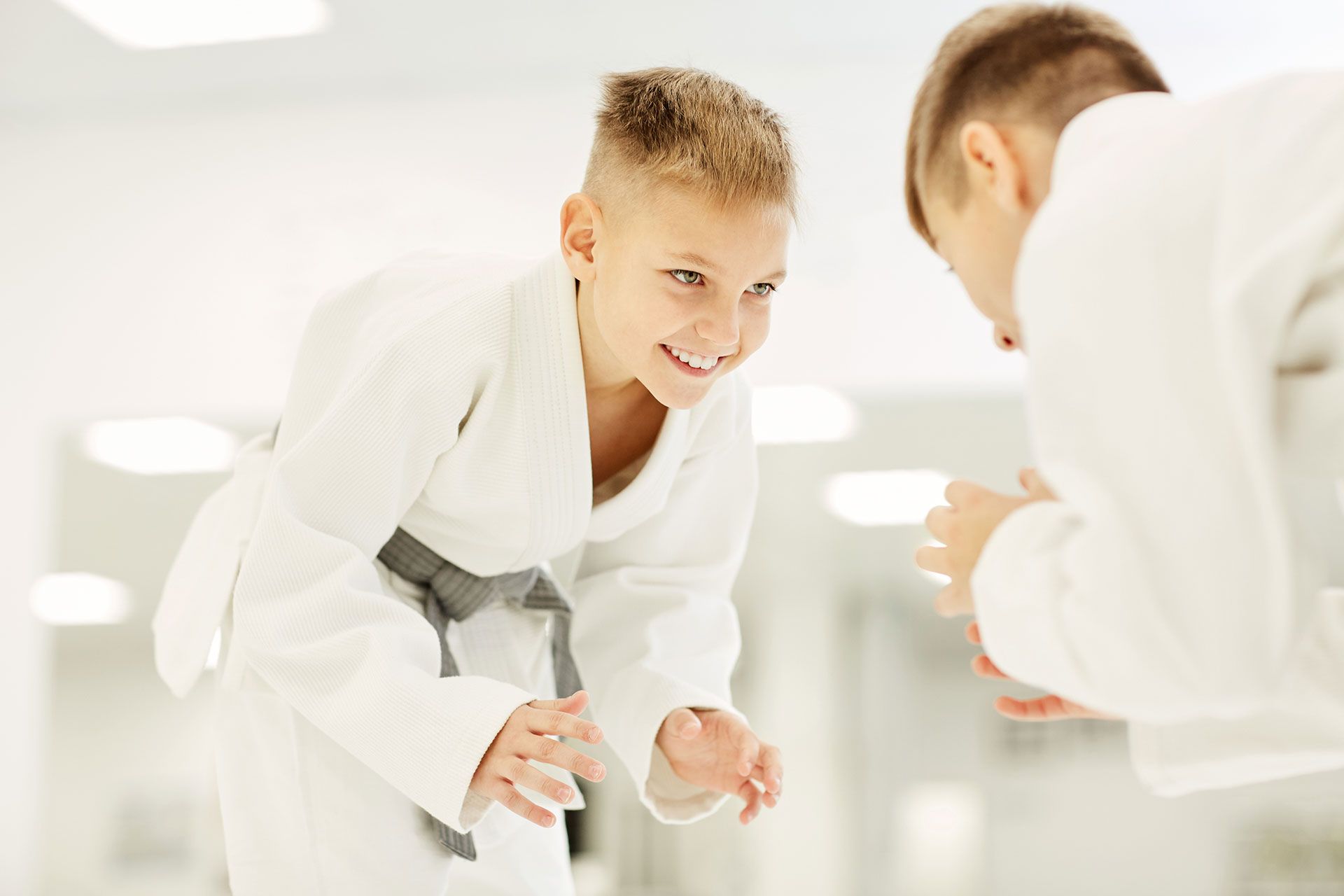 Two young boys are practicing judo in a gym.