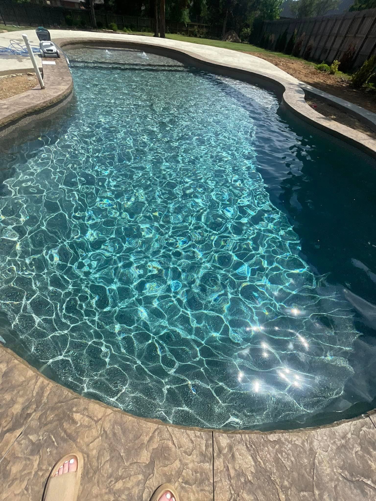 A person is sitting on the edge of a swimming pool.
