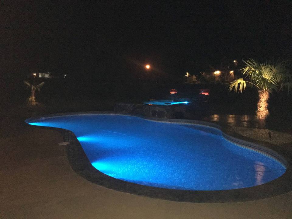 A large swimming pool is lit up at night