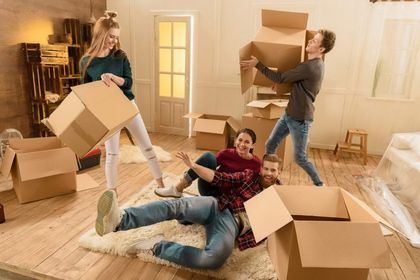 A group of people are playing with cardboard boxes in a living room.