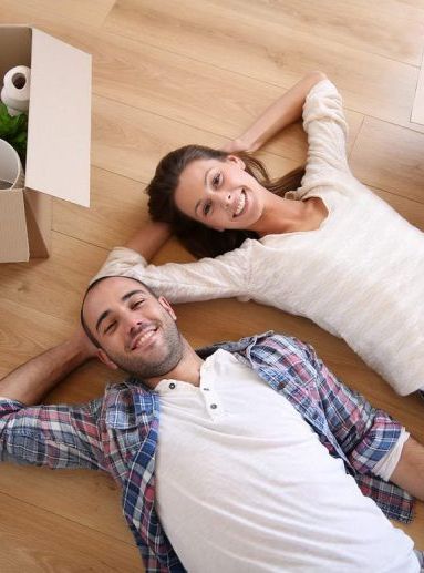 A man and a woman are laying on the floor next to a cardboard box.