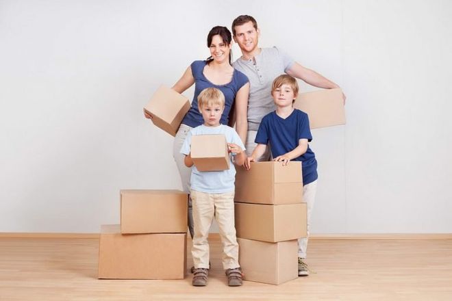 A family is standing next to a pile of cardboard boxes.