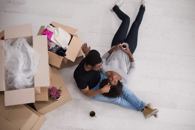 A man and a woman are laying on the floor next to boxes.