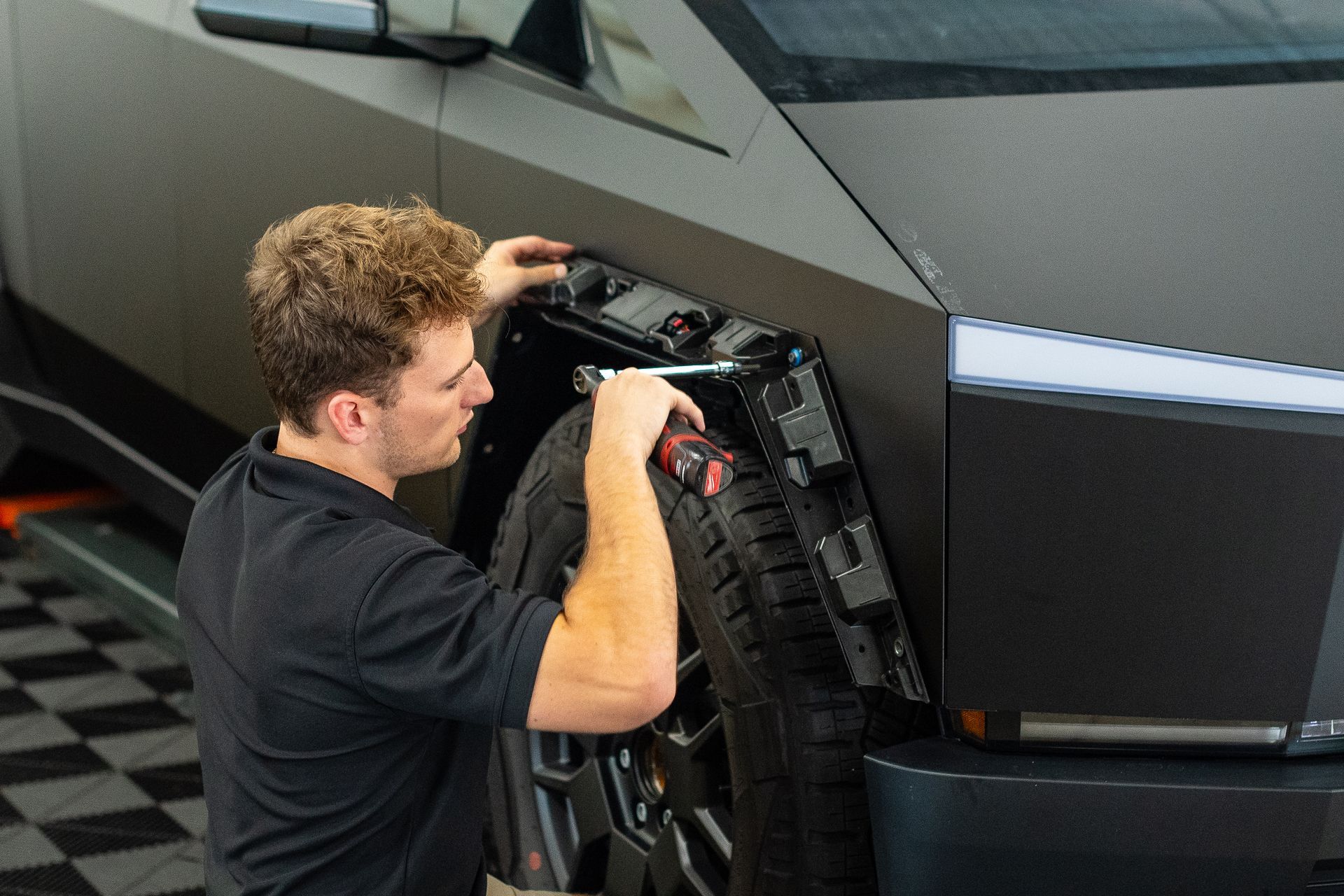 A man is working on a tesla model s in a garage.