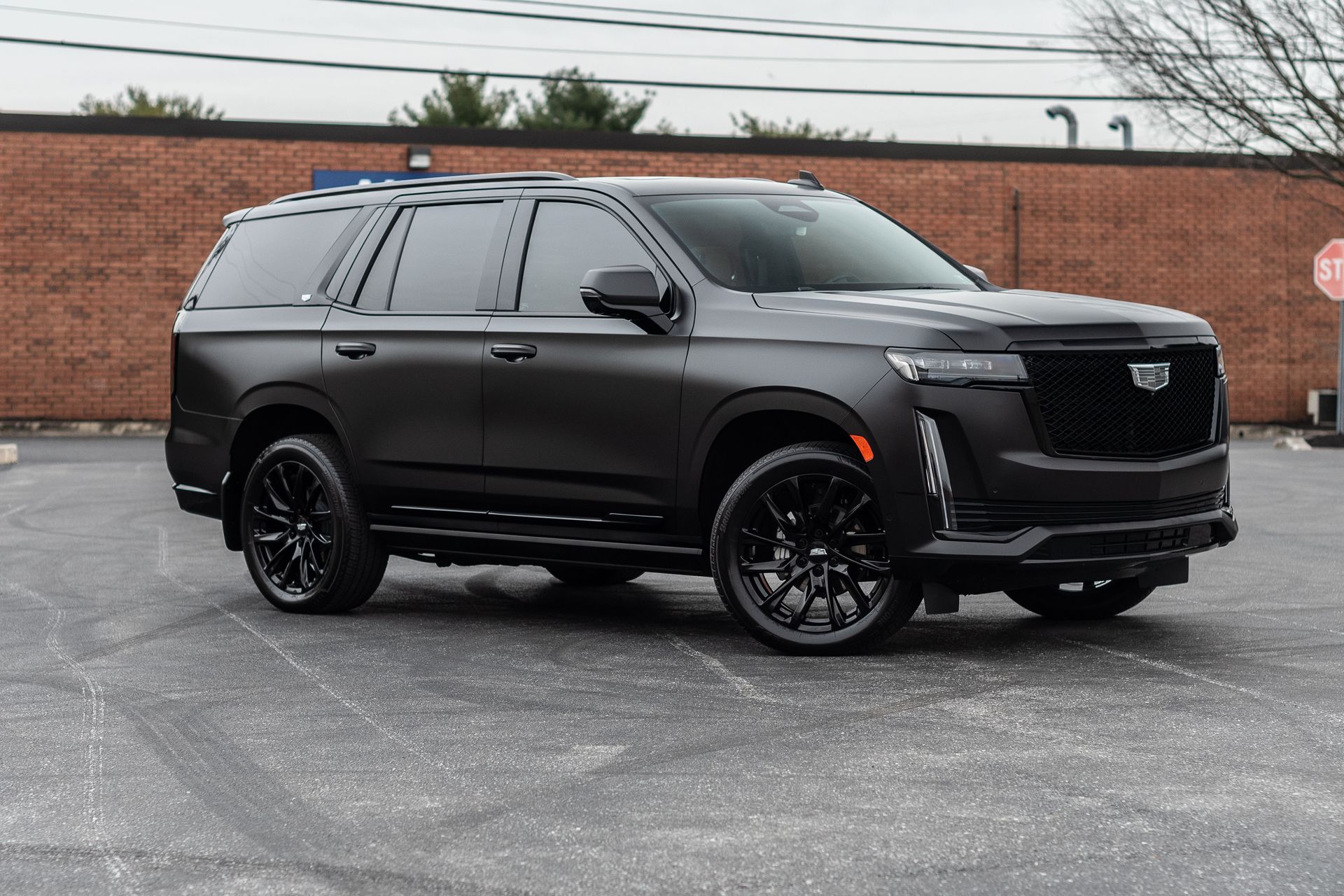 A black cadillac escalade is parked in a parking lot.