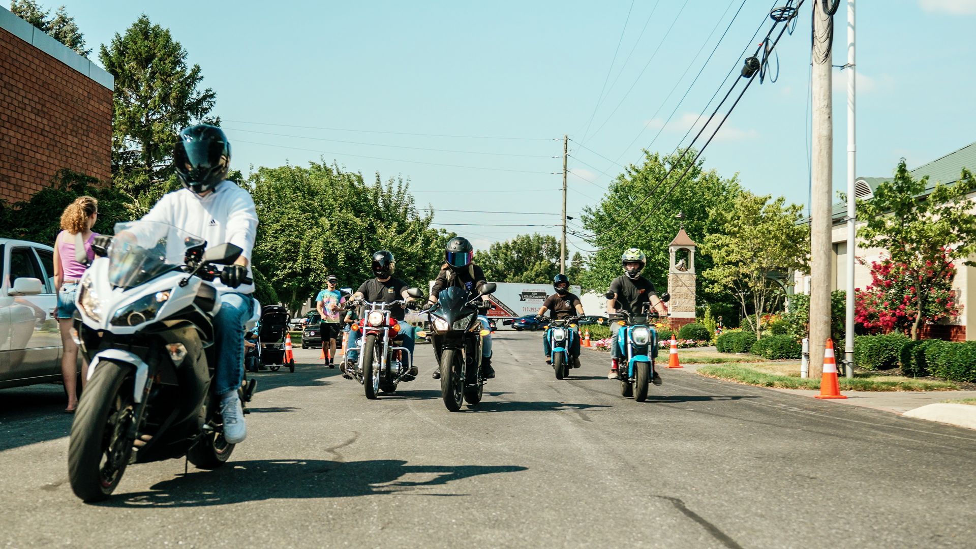 A group of people are riding motorcycles down a street.