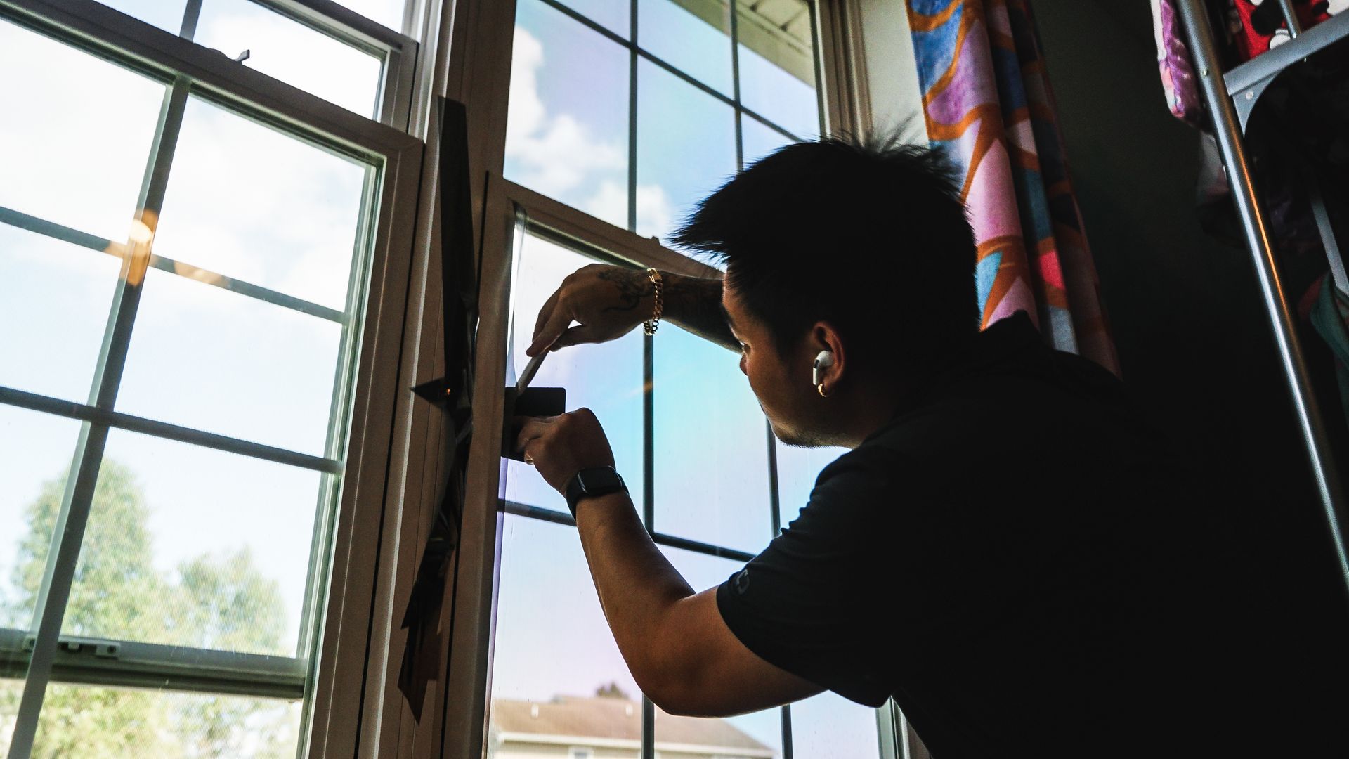 A man is fixing a window with a screwdriver.