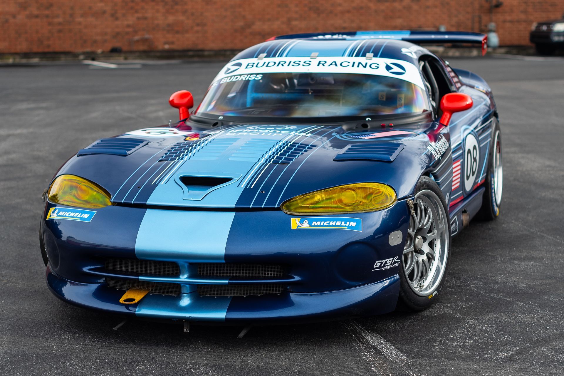 A blue race car with the number 67 on the front is parked in a parking lot