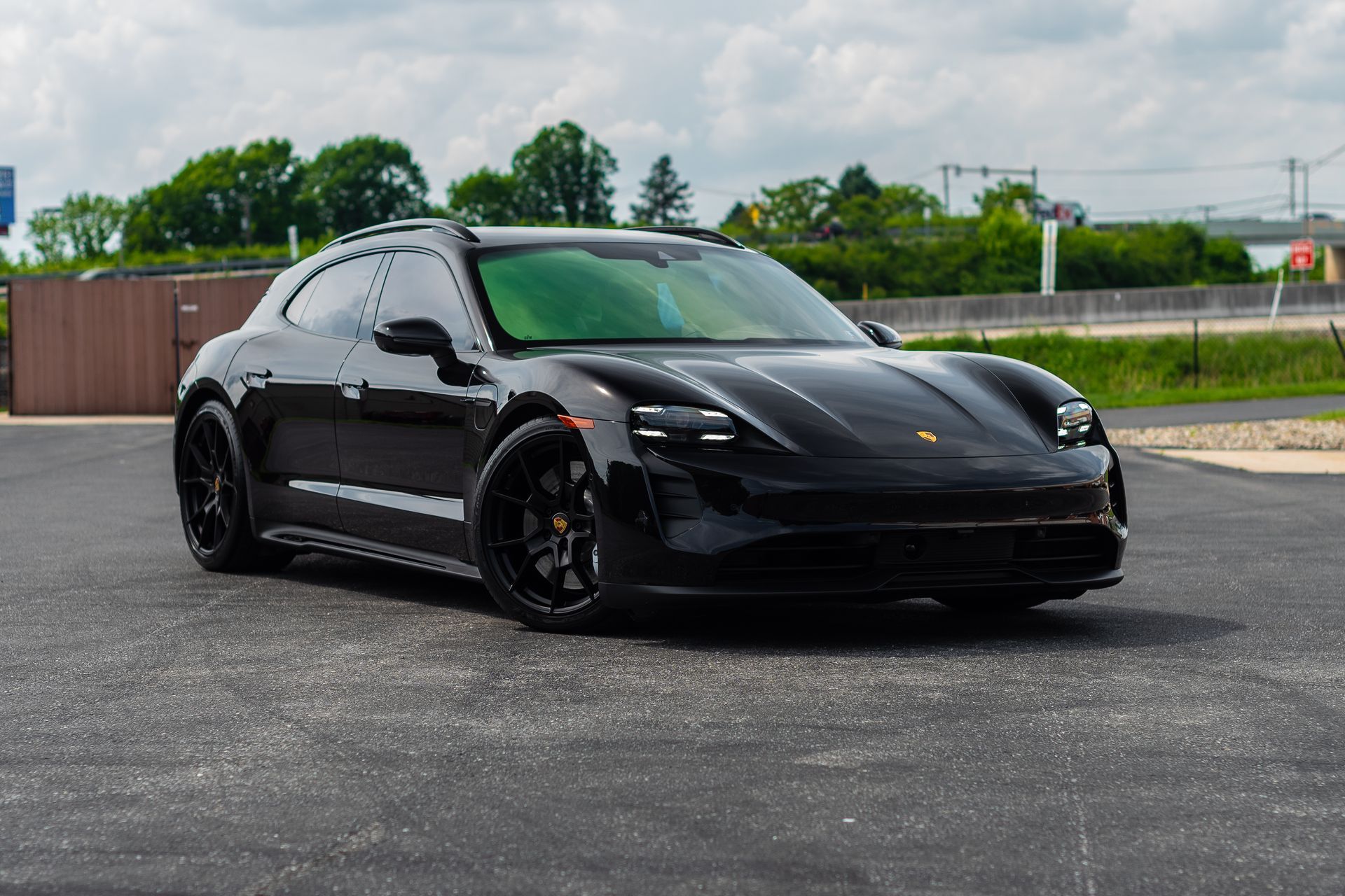 A black porsche taycan turbo s is parked in a parking lot.