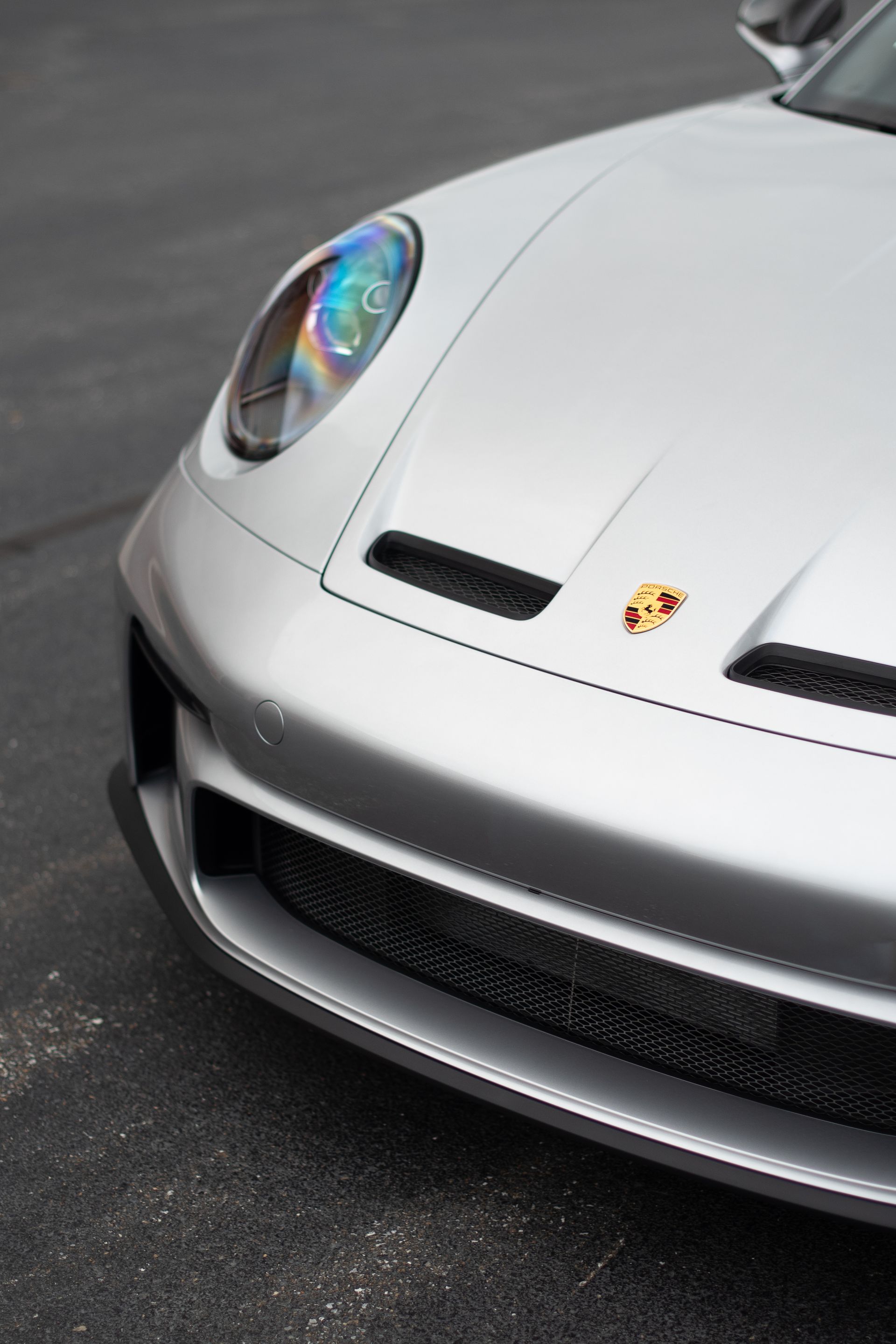 A silver porsche is parked on the side of the road