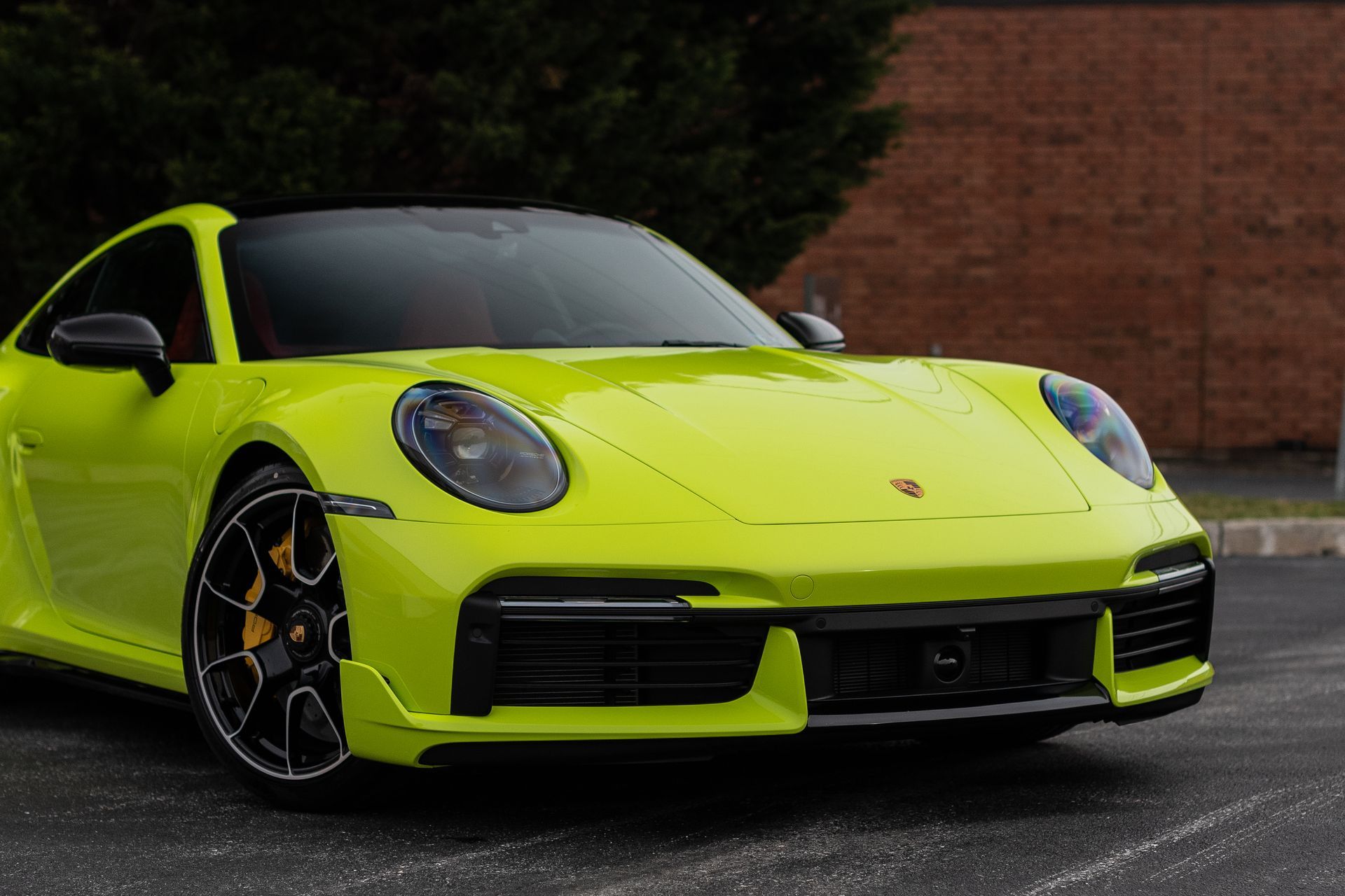 A bright yellow porsche 911 turbo s is parked in a parking lot.