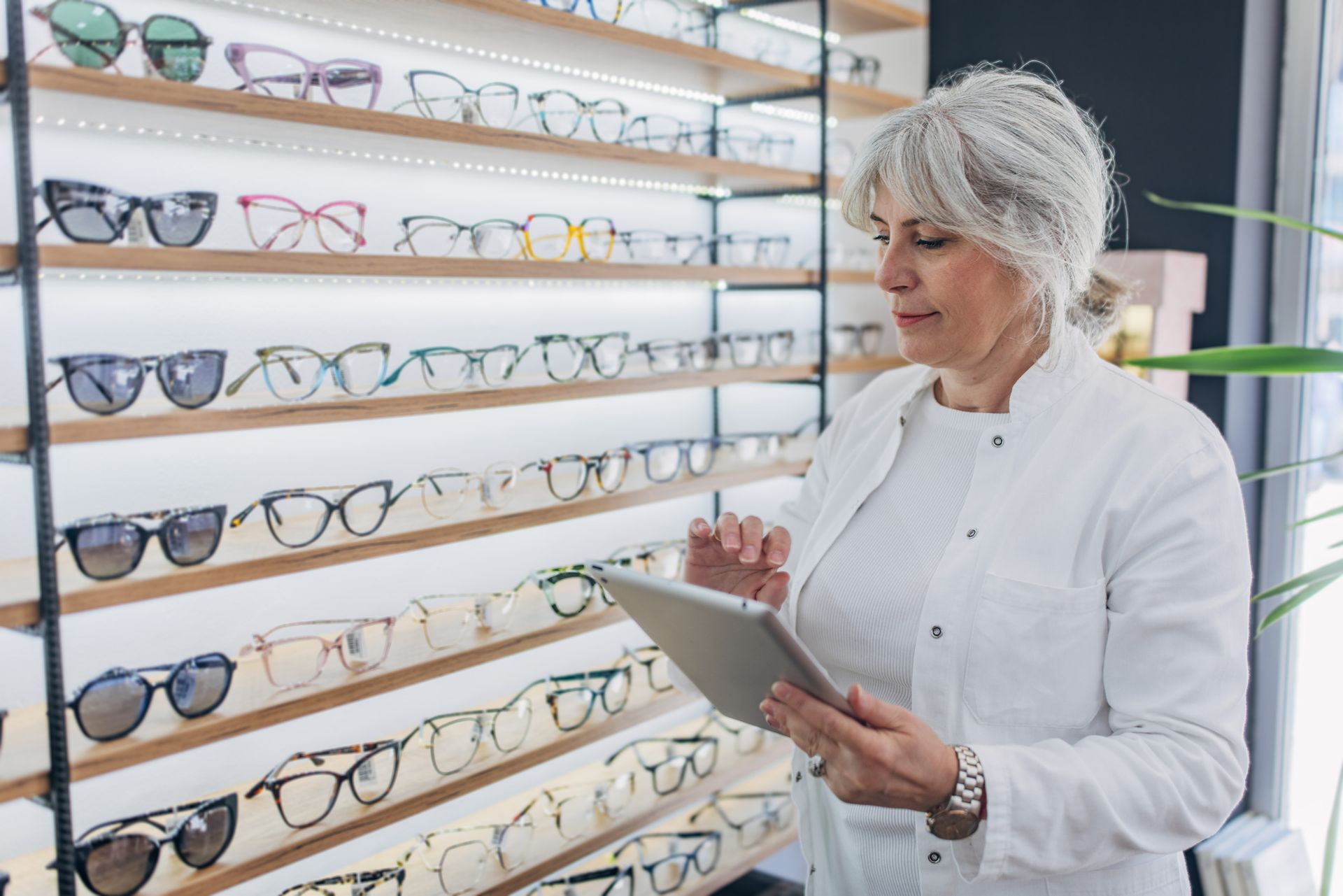 A woman is looking at a tablet in an optical shop. A woman is looking at a tablet in an optical shop.