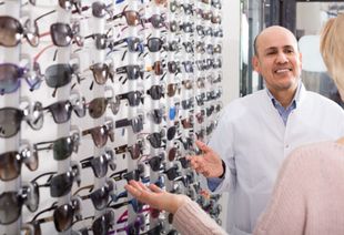 A man is talking to a woman in an optical shop about sunglasses.