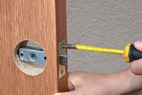 Installing the door handle with a latch in the interior doors, close-up hands of the installer with a screwdriver.