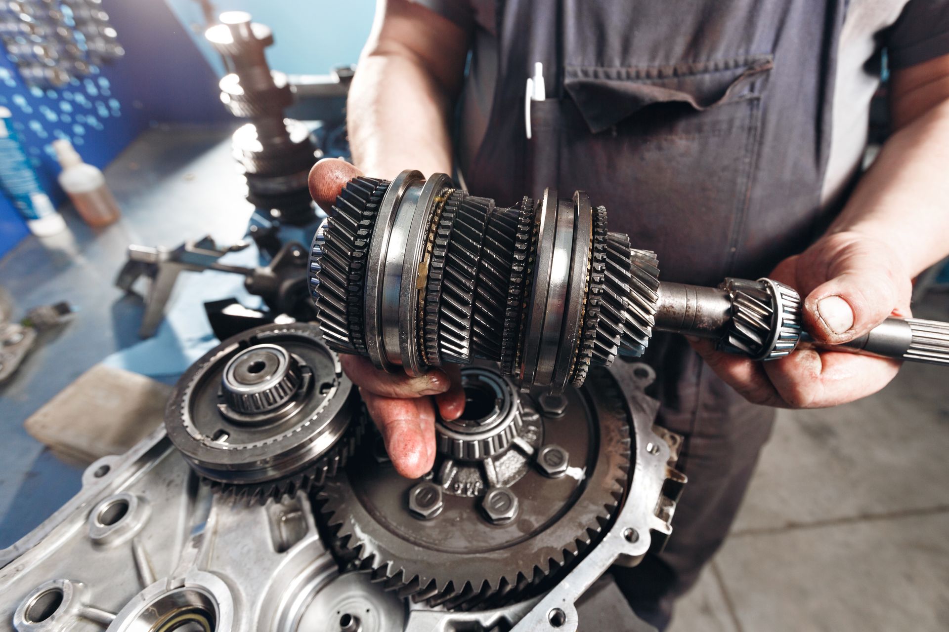 Mechanic holding an exposed car transmission assembly with interlocking gears.
