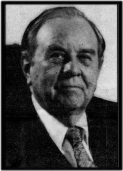Man in a suit and tie, looking forward with a serious expression.
