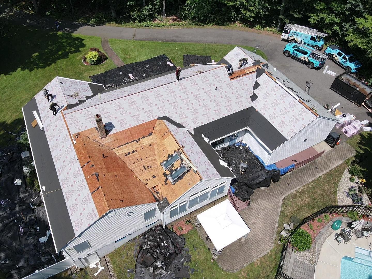 Aerial view of a house roof partially under construction; shingles being replaced.