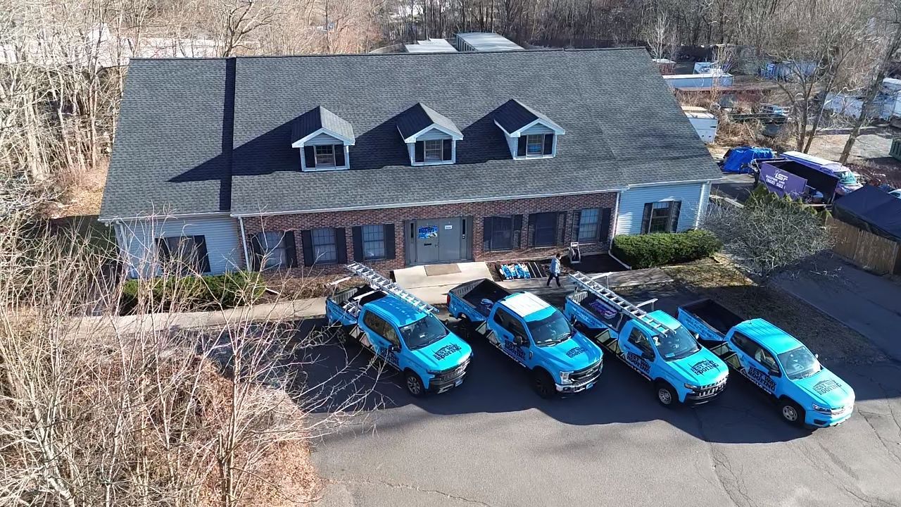 Blue trucks parked in front of a house with a dark gray roof.