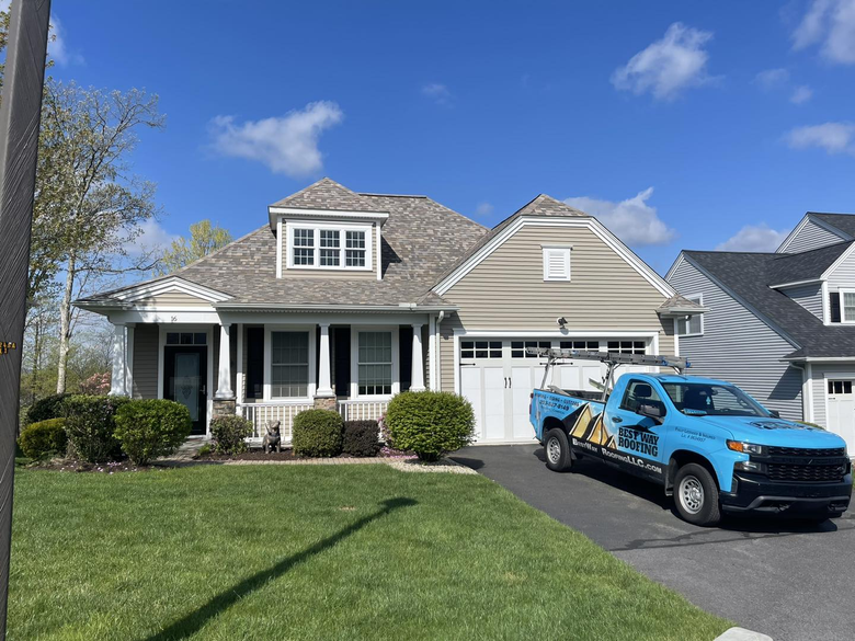 Tan house with a blue work truck parked in front; blue sky overhead.