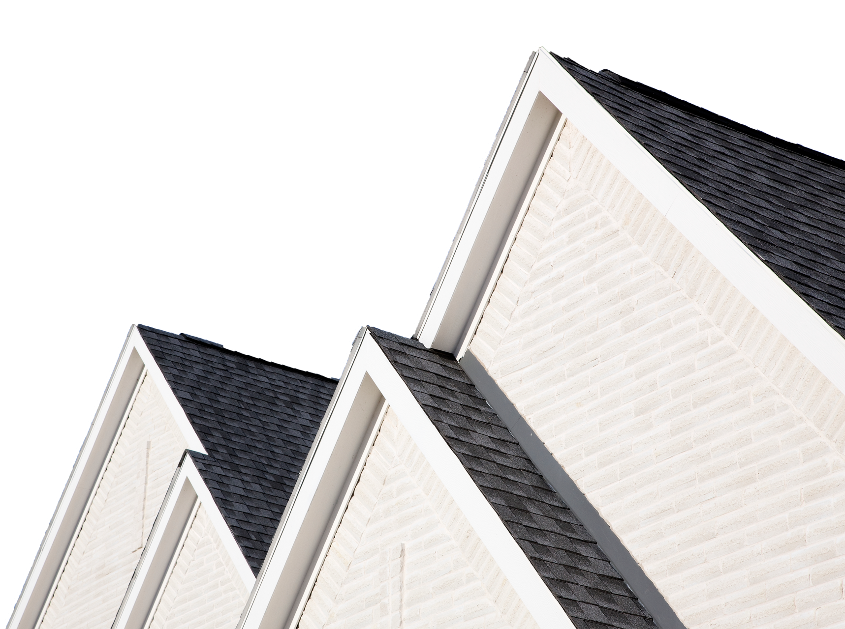 Close-up of white brick house peaks with dark shingled roofs against a white sky.