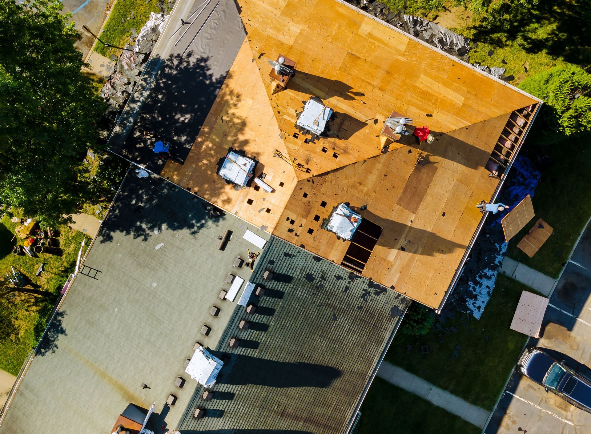 Aerial view of a building roof with vents, trees, and surrounding walkways.