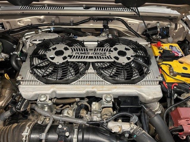 A close up of a car engine with two PTV fans on it.