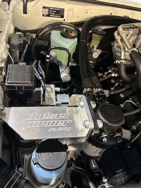 A close up of an unpainted DPU Pre Fuel Kit in the engine of a car.