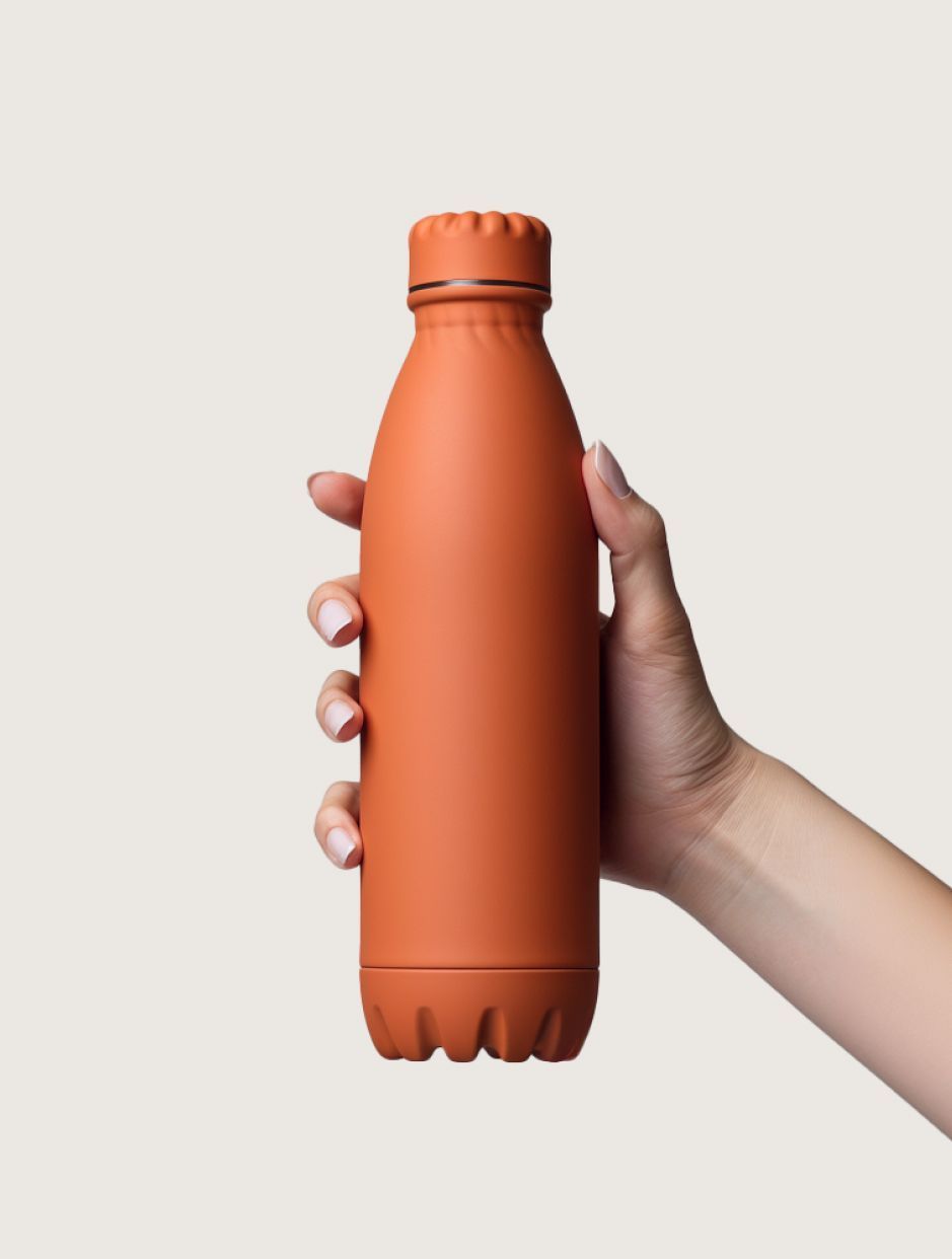 Hand holding an orange insulated water bottle against a light background