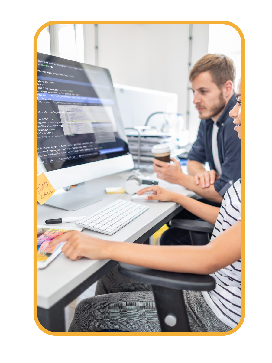 A man and a woman are sitting at a desk in front of a computer designing a website