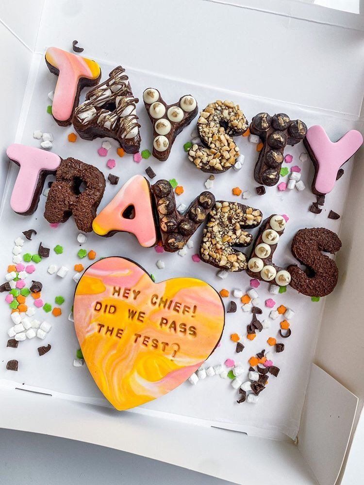 A box filled with cookies and sprinkles that say taystey travels