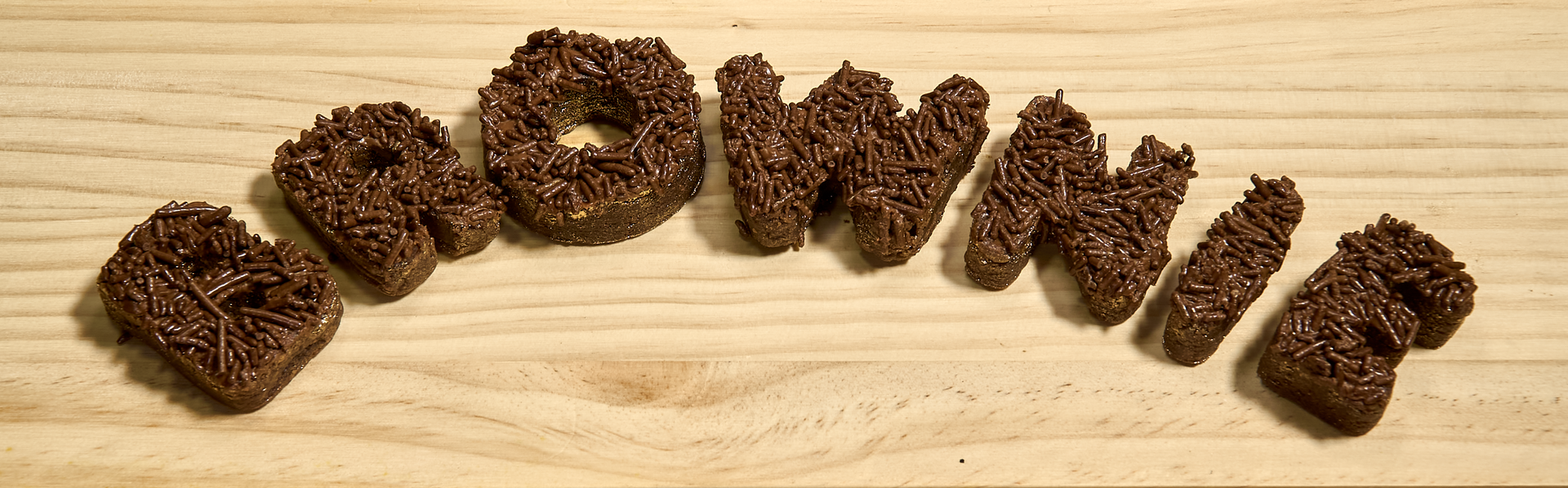 The word brownie is written in chocolate on a wooden surface
