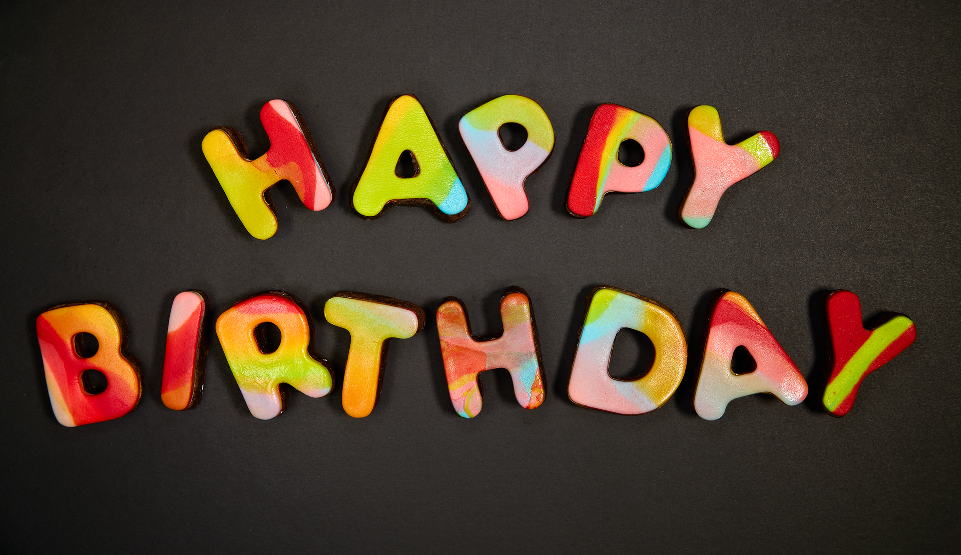 The word happy birthday is written in colorful letters on a black background