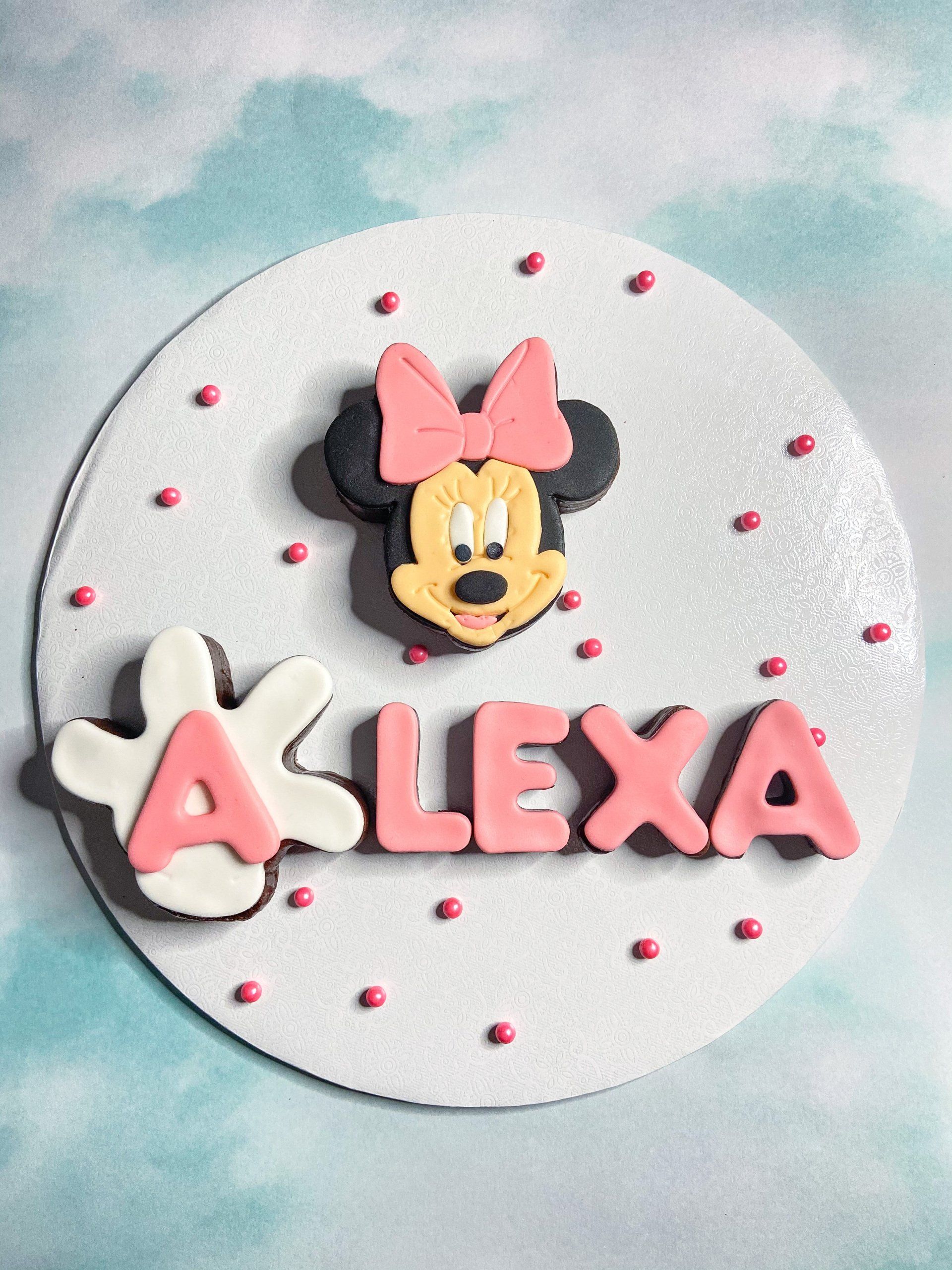 A cake decorated with minnie mouse and the name alexa