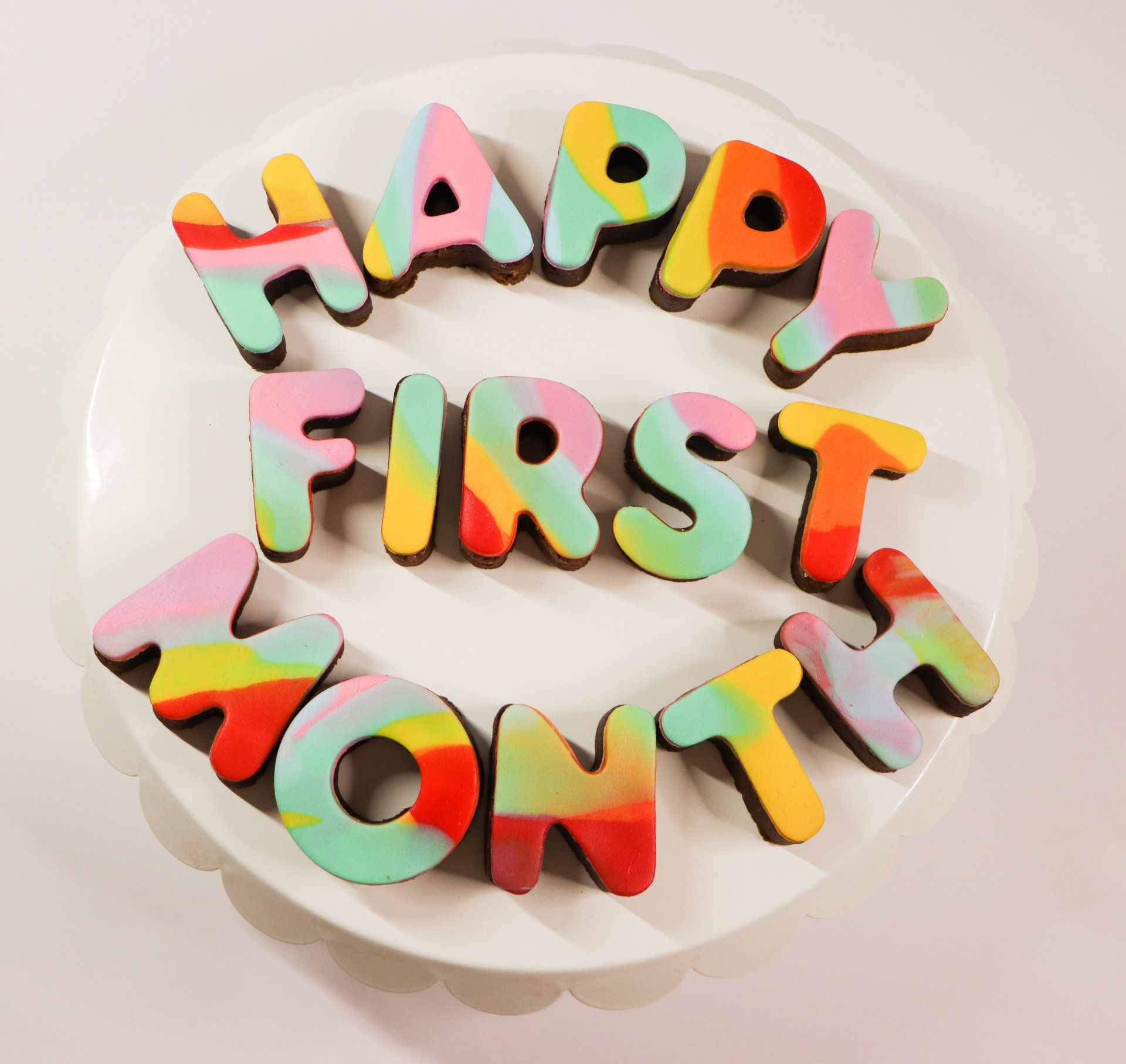 A white plate with colorful letters that say happy first month