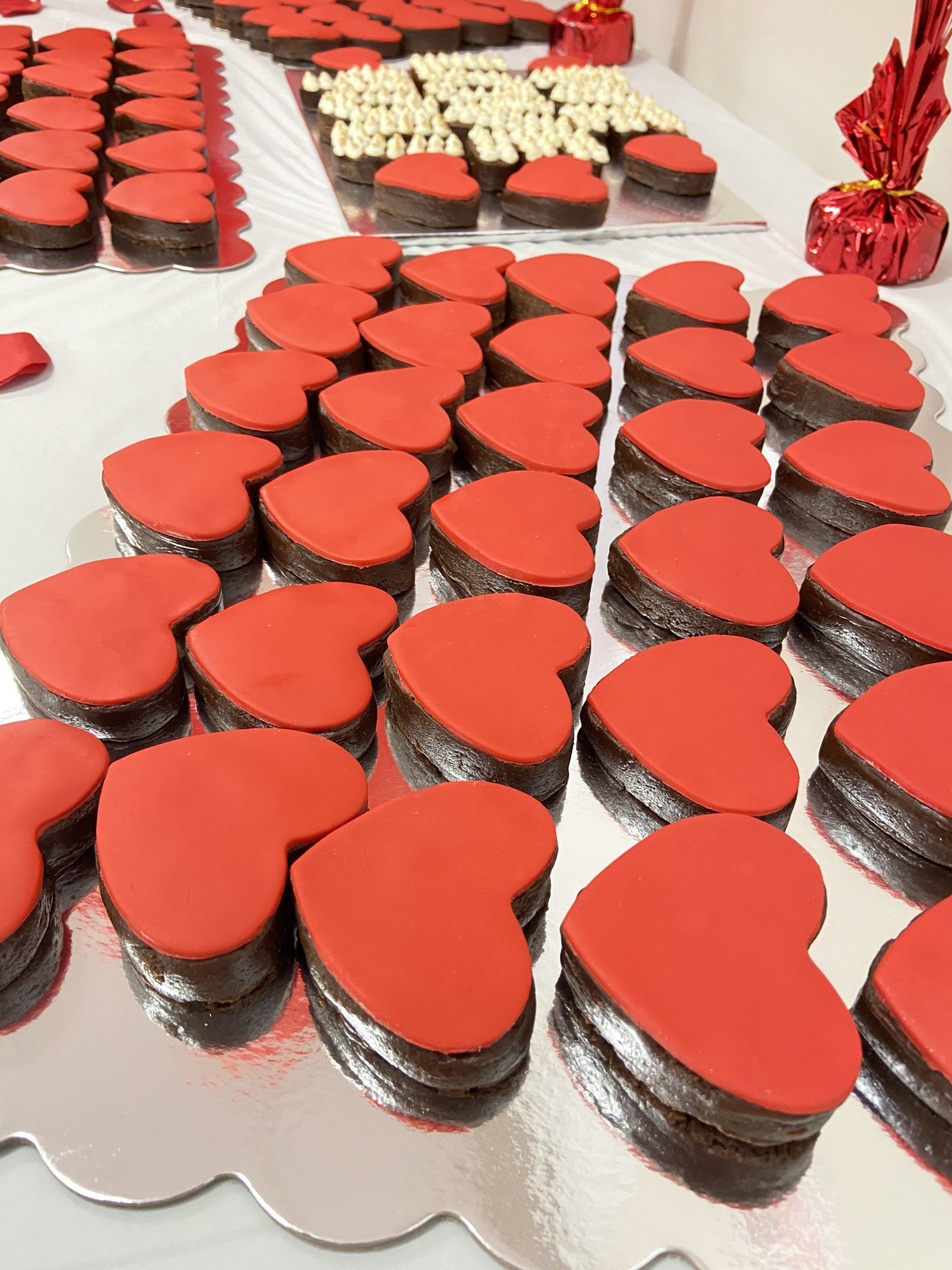 A bunch of heart shaped cookies with red frosting