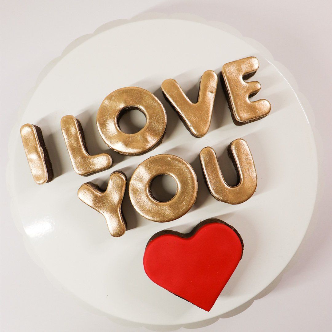 A white plate with i love you cookies and a red heart