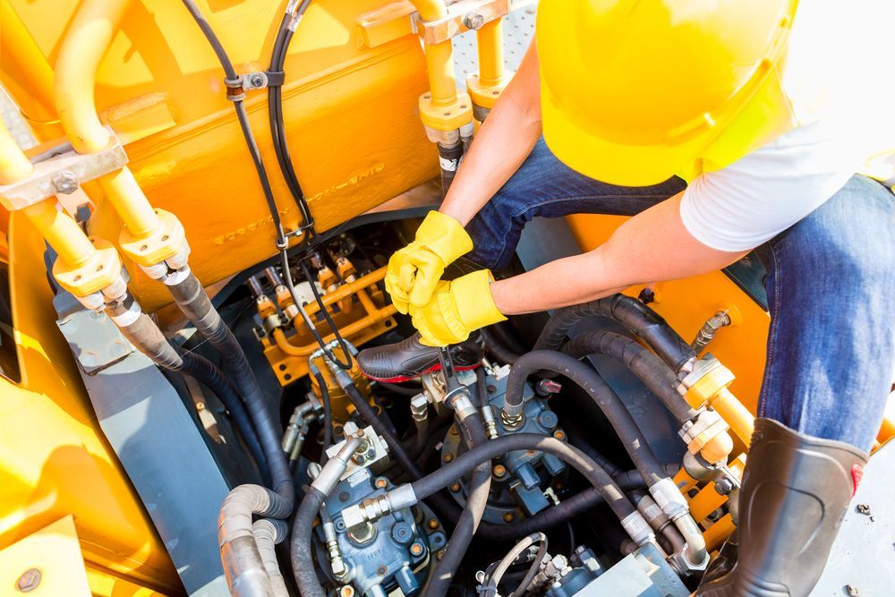 A Man In A Hard Hat Is Working On The Engine Of A Machine — Blue Diesel & Equipment In Speewah, QLD