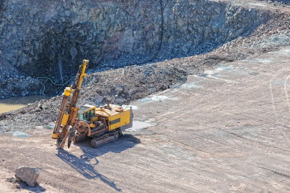 A Yellow Drilling Machine is Driving Through a Dirt Field in a Quarry — Blue Diesel & Equipment In Weipa, QLD