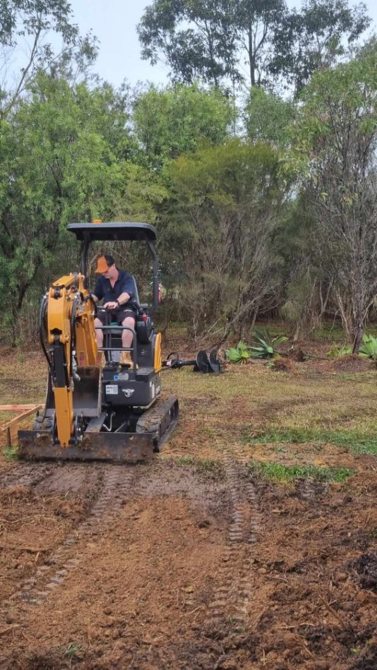 A Man Is Driving A Bulldozer In A Dirt Field — Blue Diesel & Equipment In Speewah, QLD