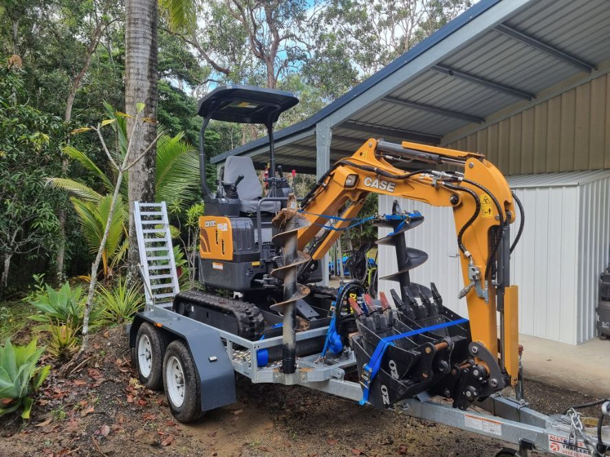 A Small Excavator Is Parked On A Trailer In Front Of A Garage — Blue Diesel & Equipment In Speewah, QLD