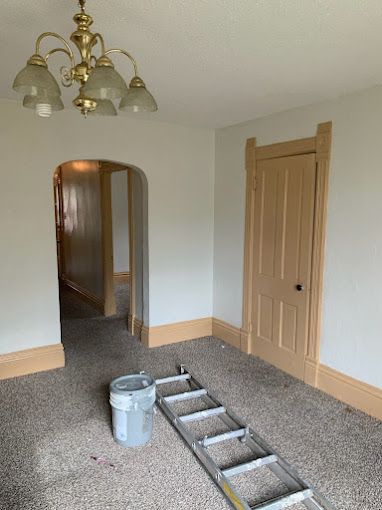 An empty room with a ladder and a bucket of paint.